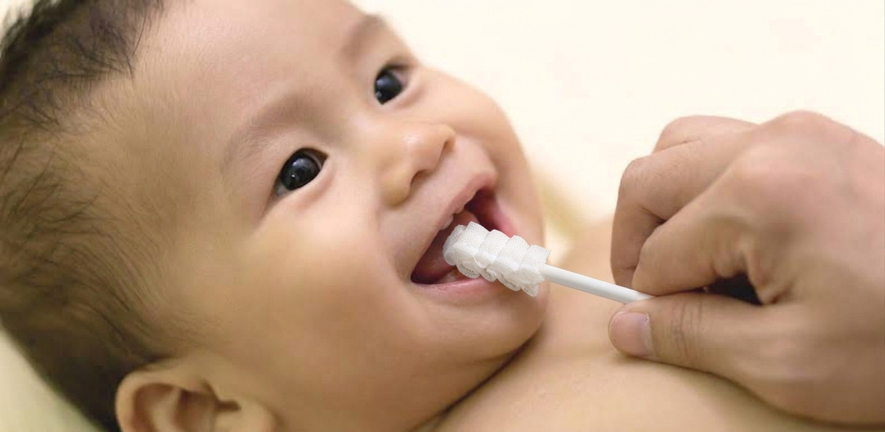 Mother gently cleaning her baby's gums